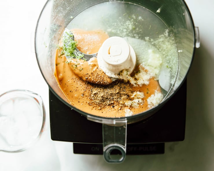 An overhead shot of a food processor with peanut butter lime dressing ingredients inside, pre-mixing.