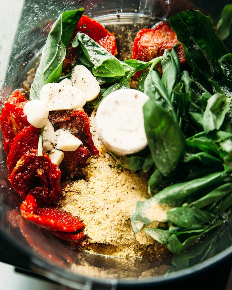 An overhead shot of vegan pesto ingredients in a food processor.