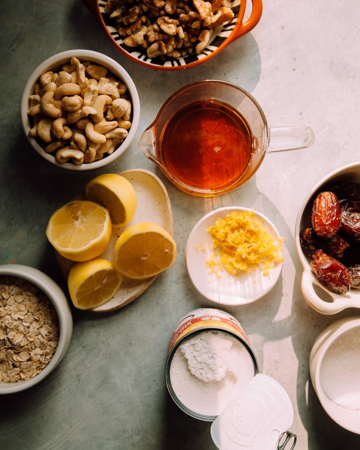 An overhead shot of ingredients fort creamy vegan lemon bars in direct sunlight in a blue-ish grey background.