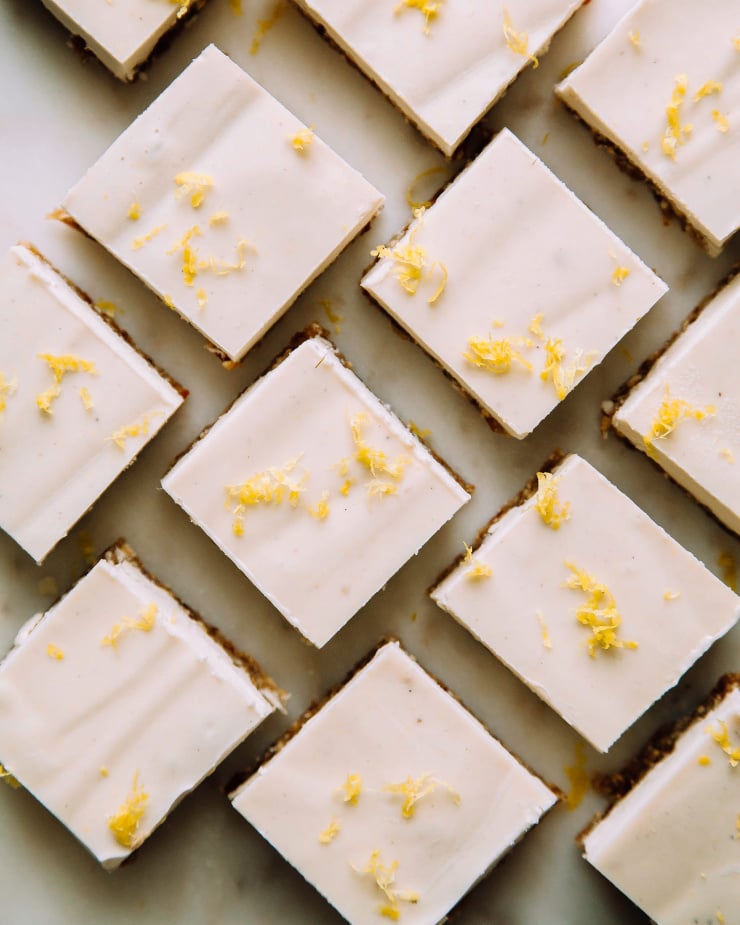 An overhead shot of creamy vegan lemon bars, cut into squares and garnished with lemon zest.