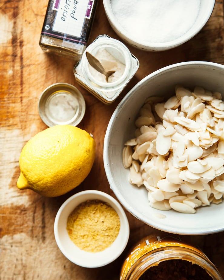 An overhead shot of ingredients for a vegan almond ricotta on top of a worn wood cutting board.