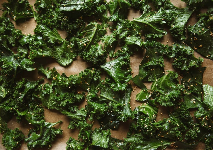 Image shows a bunch of kale leaves coated in oil, before roasting.
