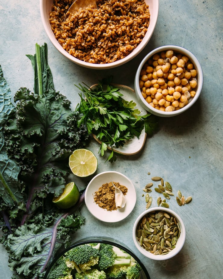 An overhead shot of ingredients for vegan green goddess bowls over a blue background.
