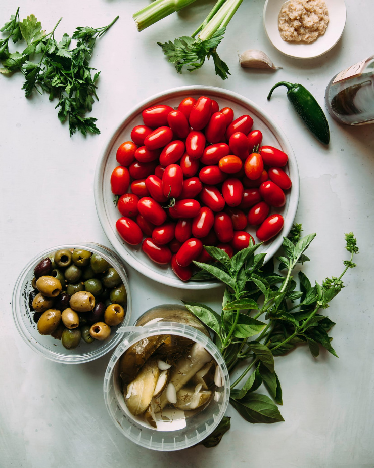 An overhead shot of ingredients for Bloody Mary bruschetta on a white background.