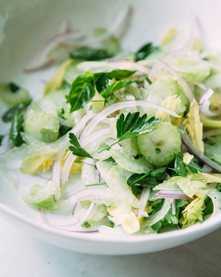 An up close, overhead shot of a wispy salad to top bruschetta that includes: celery, red onion, and parsley.