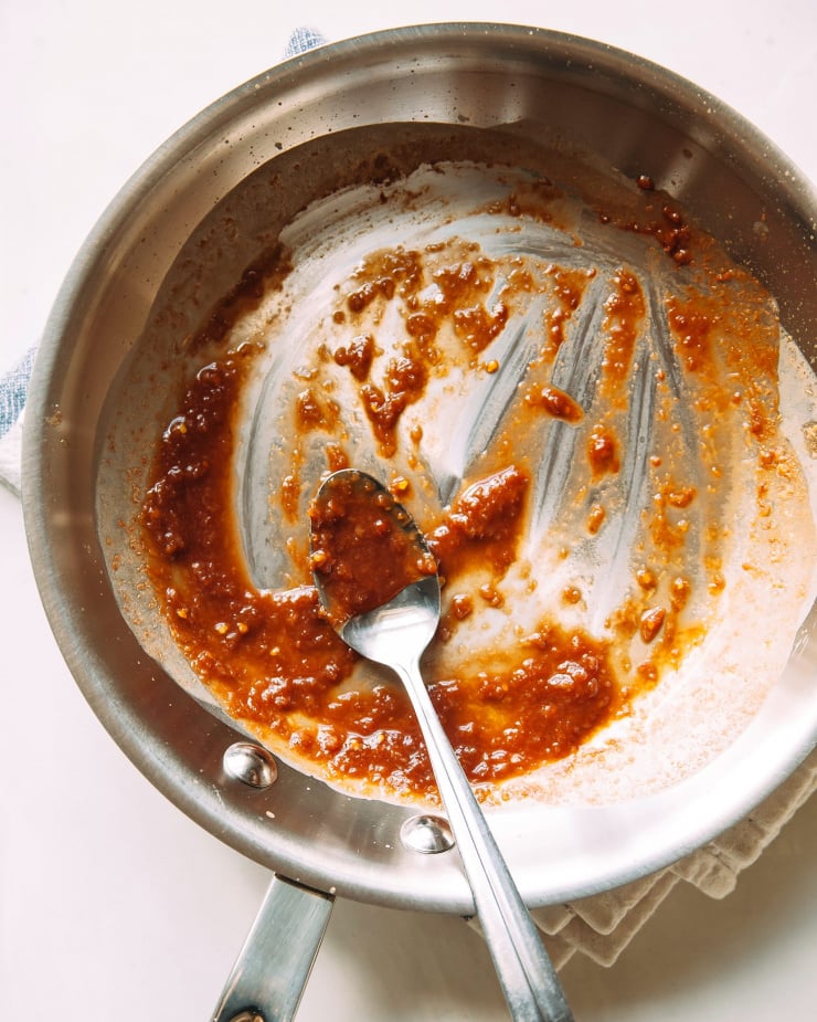 An overhead shot of tomato reduction in a small stainless skillet.