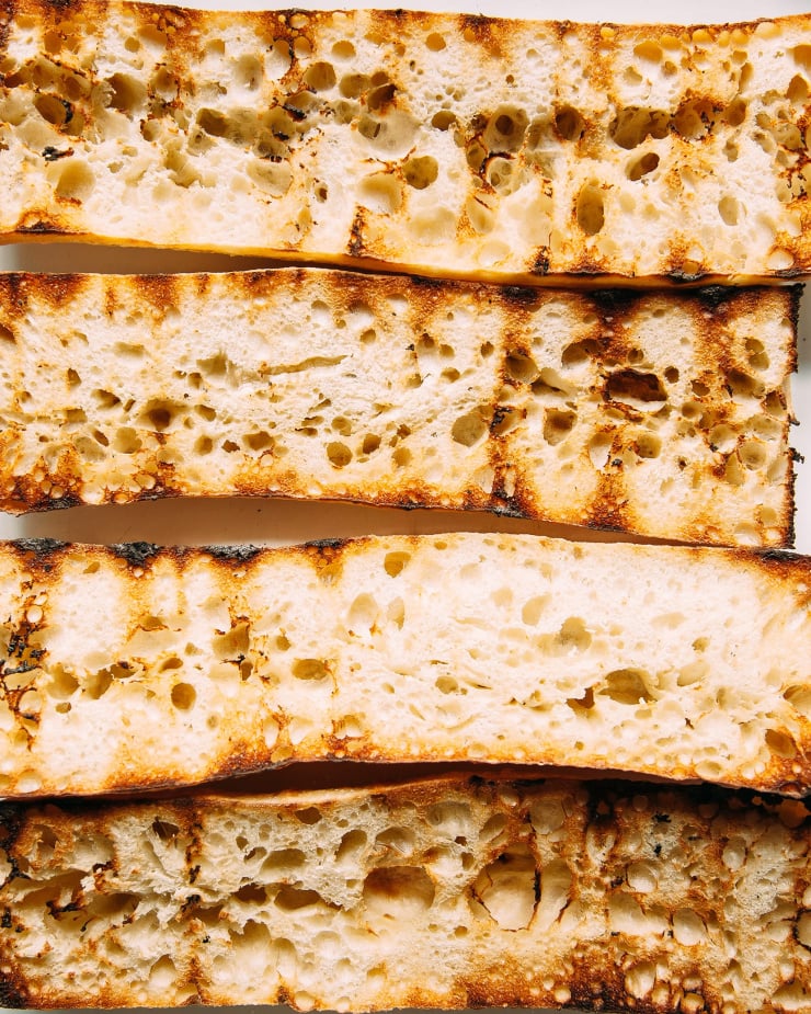 An overhead shot of split open ciabatta baguettes that have been grilled with char marks.