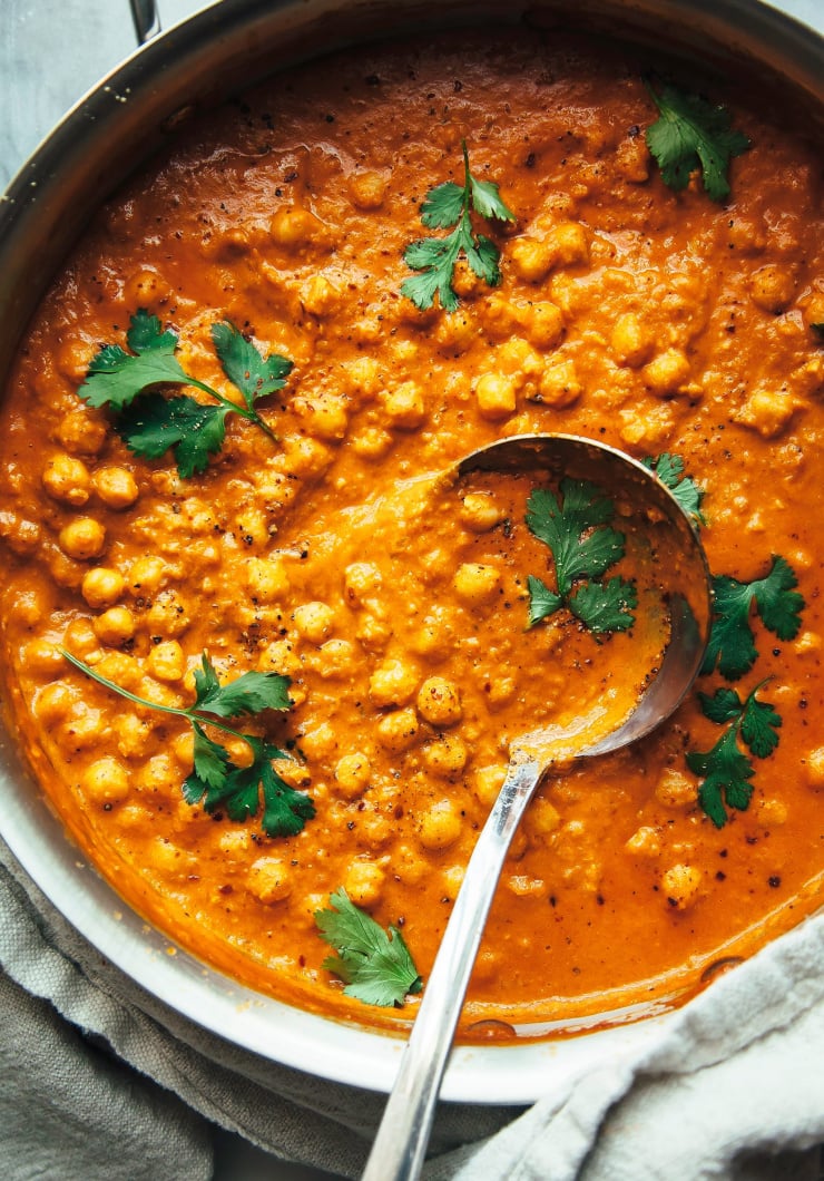 Vegan butter chickpeas in a wide skillet, shot from overhead and garnished with whole cilantro sprigs.