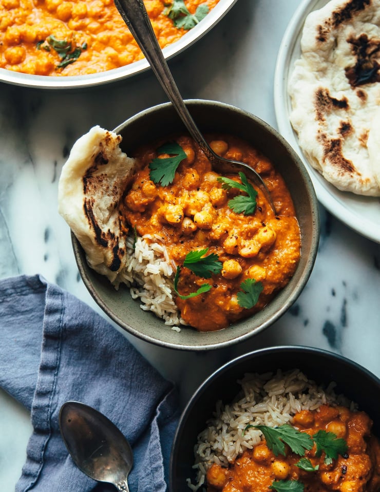 Overhead shot of vegan butter chickpeas in an individual bowl with a torn piece of flatbread to the side.