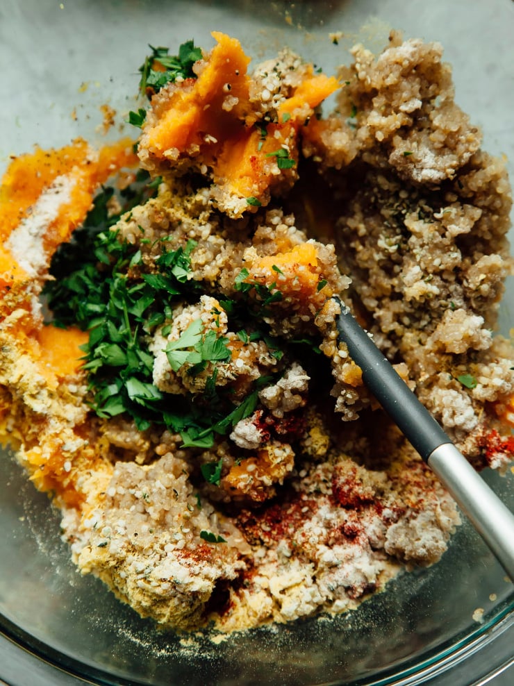 An overhead shot of a quinoa, mashed sweet potato, and herb mixture in a bowl with a spatula.