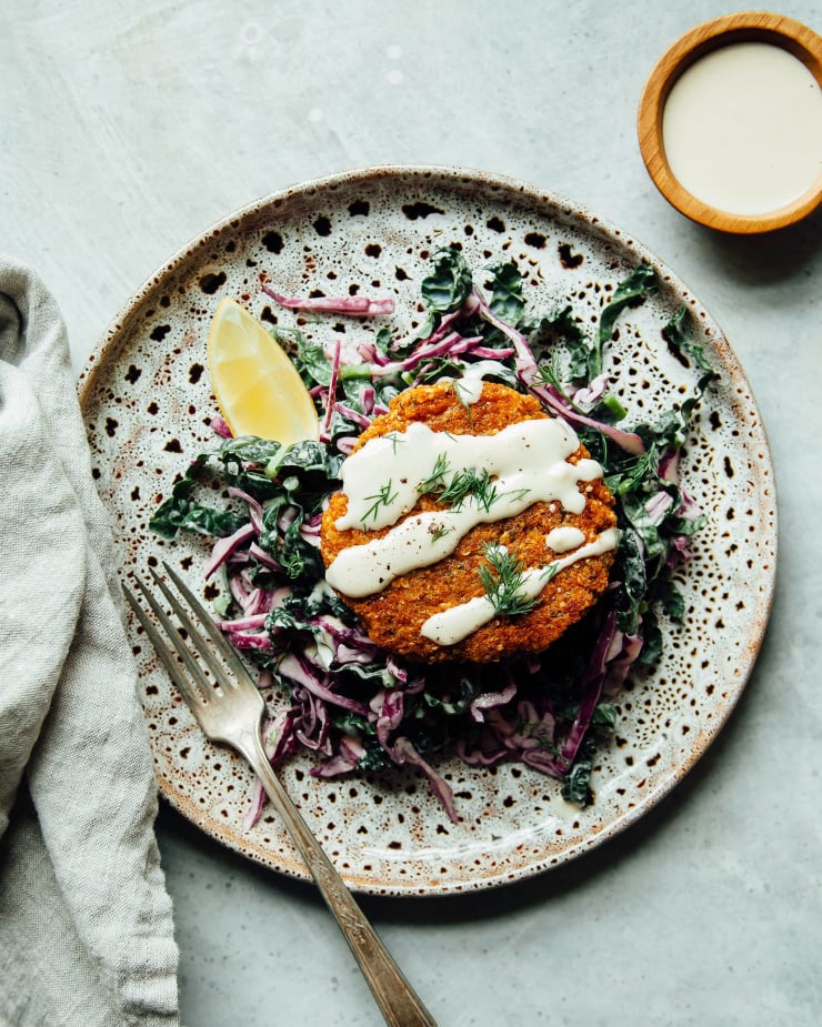 An overhead shot of a pale orange patty on top of a bed of greens. The patty is drizzled with a creamy, white sauce.
