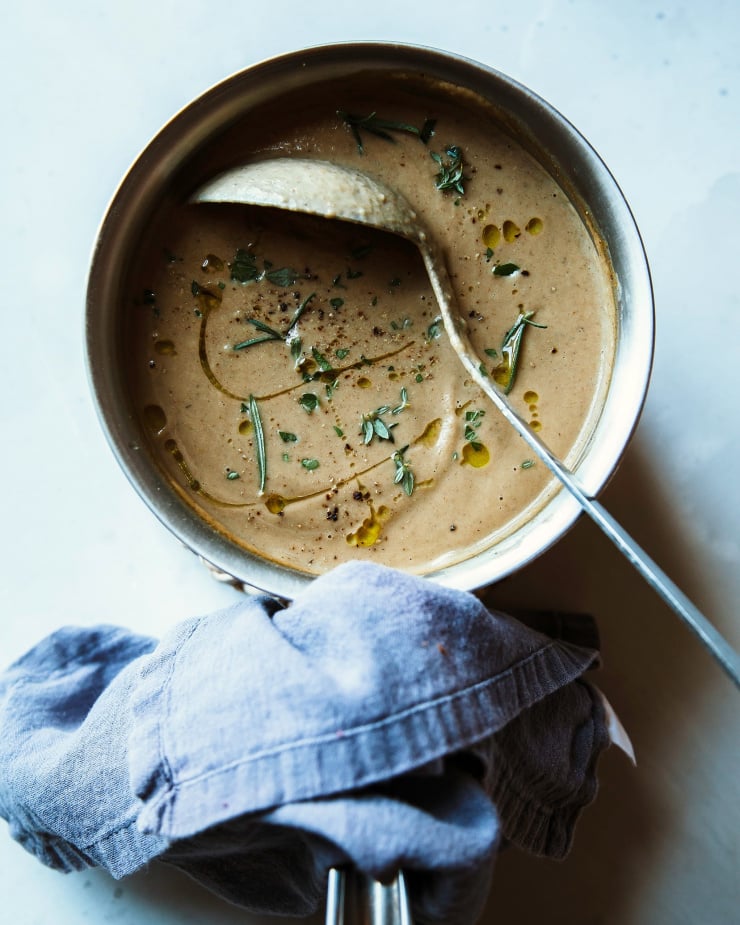 An overhead shot of vegan gravy in a small saucepan with a blue napkin on the handle.
