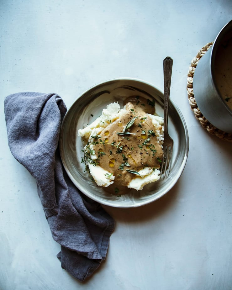 An overhead shot of vegan gravy on top of mashed potatoes in an individual serving bowl.