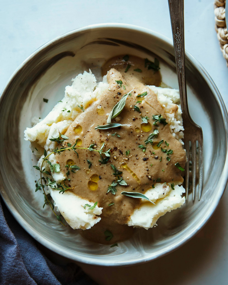 Image shows vegan gravy on top of mashed potatoes in a wide bowl.