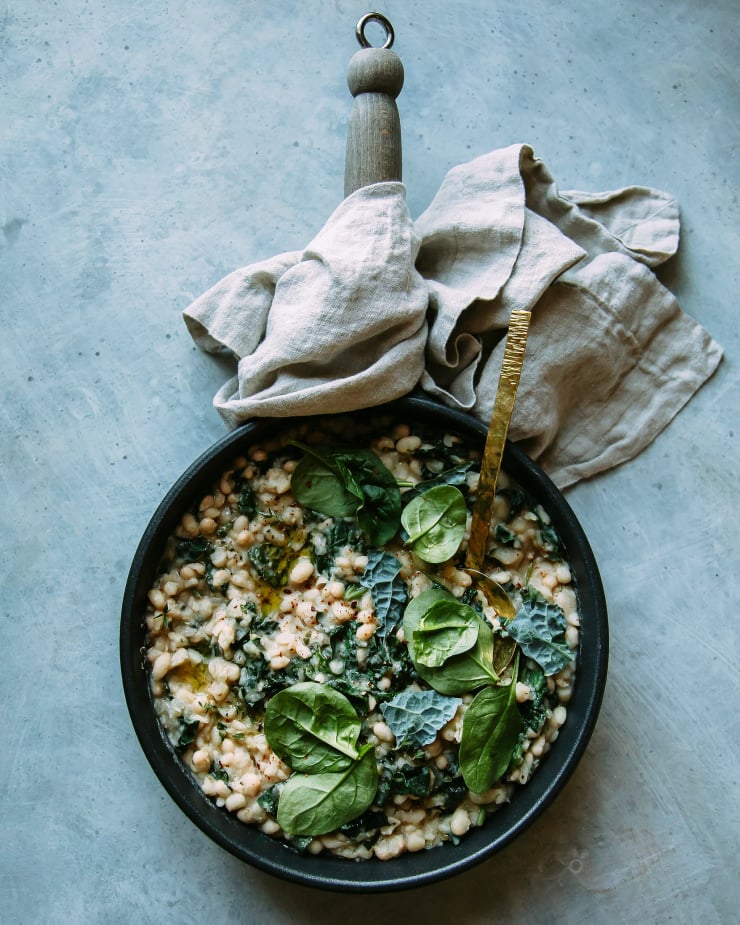 Overhead shot of creamy white beans with greens in a skillet.