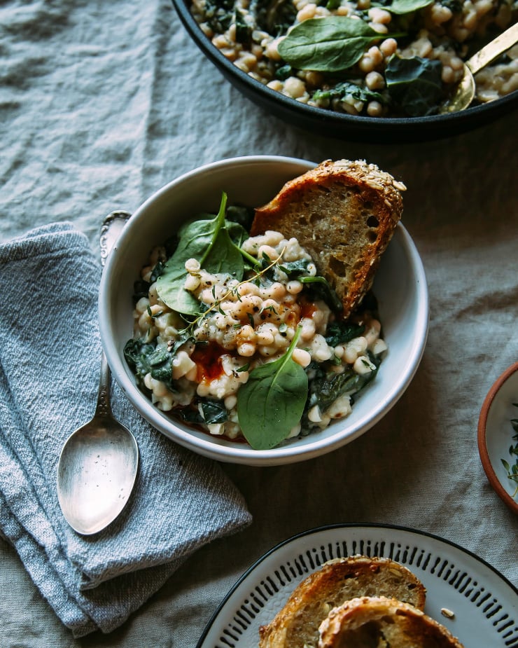 Image shows a single serving of creamy shite beans and greens with a slice of toasted bread.