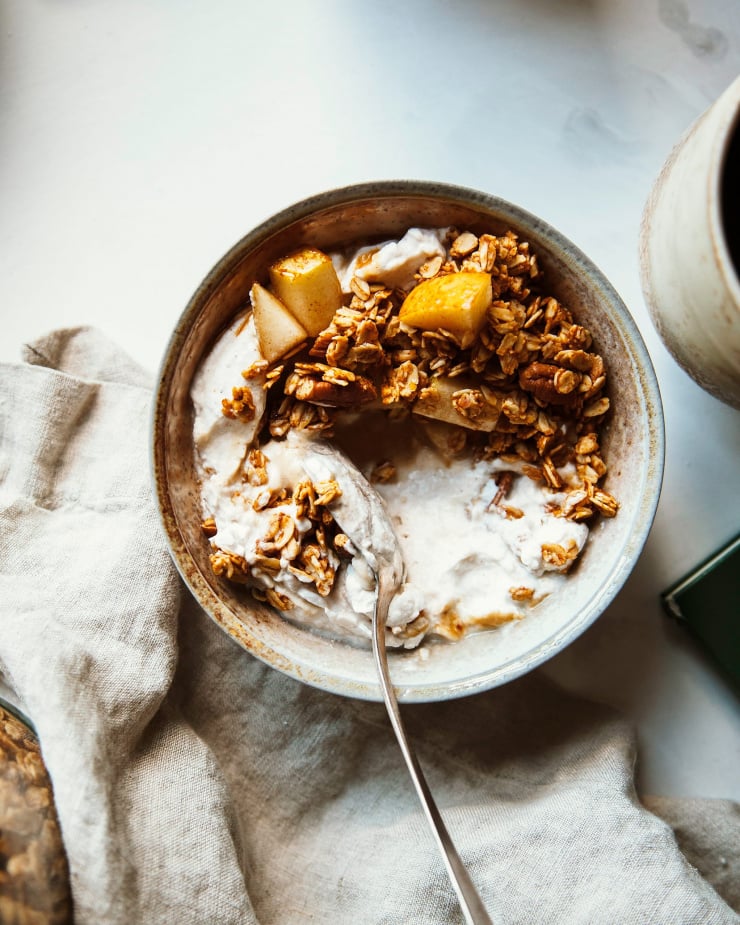 Overhead shot of sweet potato granola in a bowl with chopped pear and coconut milk granola. 