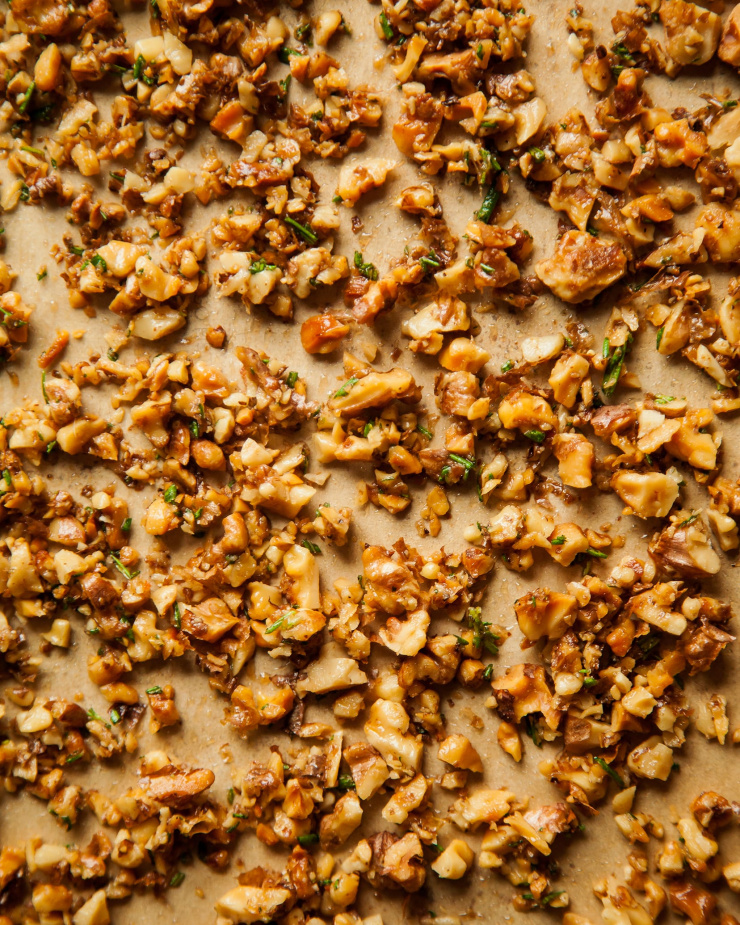 An overhead of chopped and toasted walnuts on top of parchment paper.