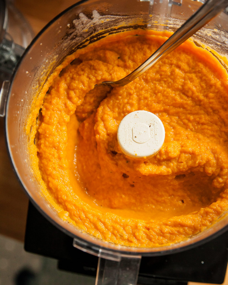 Image shows puréed sweet potatoes in the bowl of a food processor.