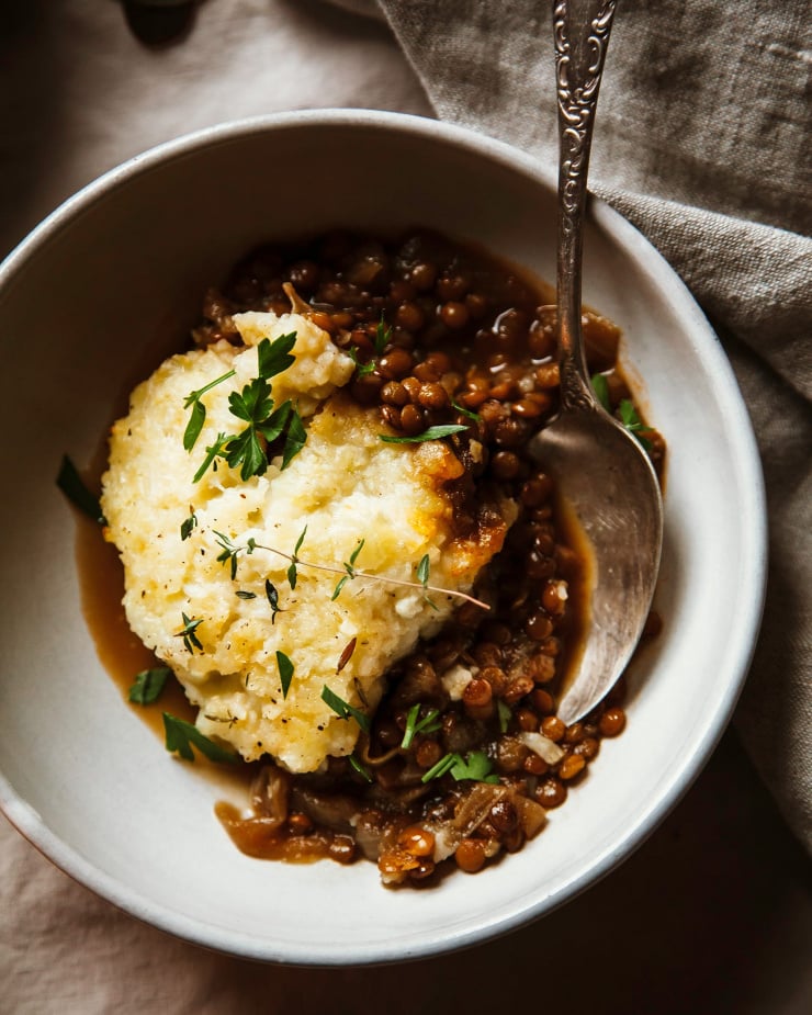 A single serving of lentil shepherd’s pie in a bowl topped with mashed potatoes and cauliflower.