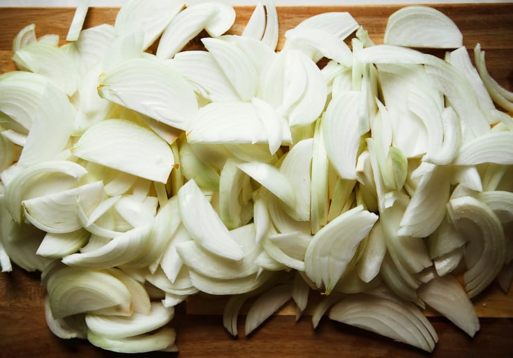 Image shows a lot of sliced onions on a cutting board.