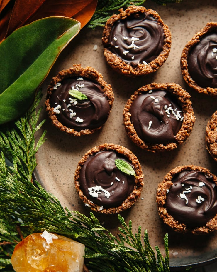 An overhead shot of chocolate ganache cups on a brown plate.