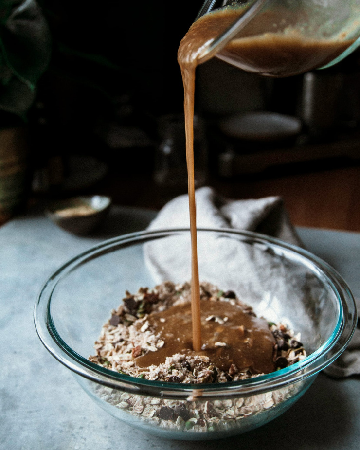 Wet ingredients being poured into a bowl of dry ingredients from up high.