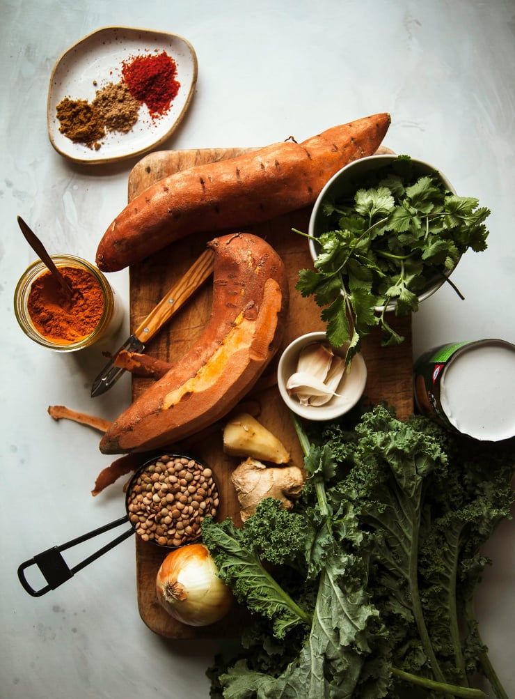 An overhead shot of ingredients used in a vegan soup recipe, all placed on a wooden cutting board.
