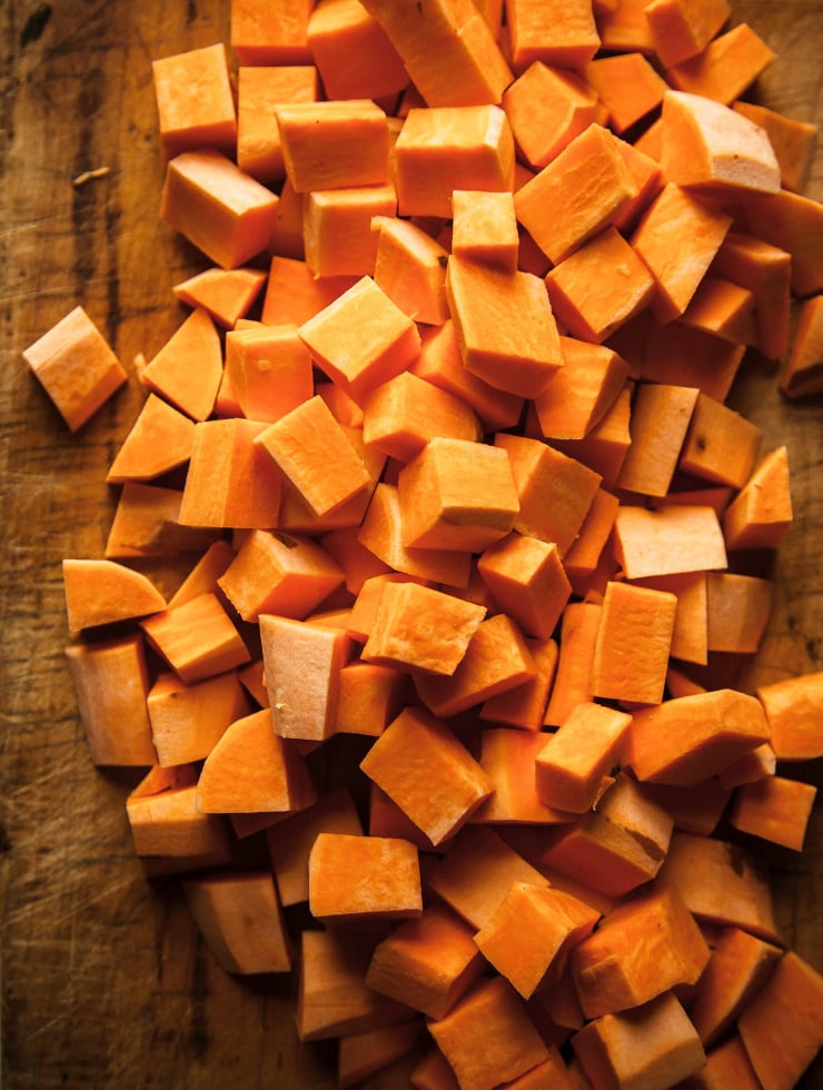 An up close, overhead shot of chopped sweet potatoes on a cutting board.