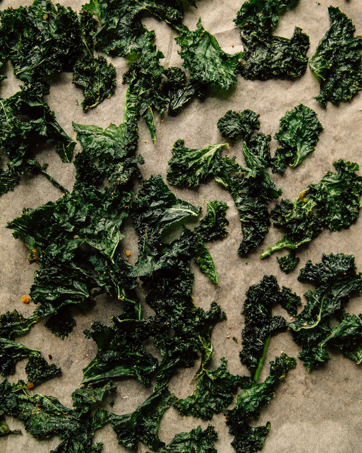 An overhead shot of crispy roasted kale on a parchment paper-lined baking sheet.