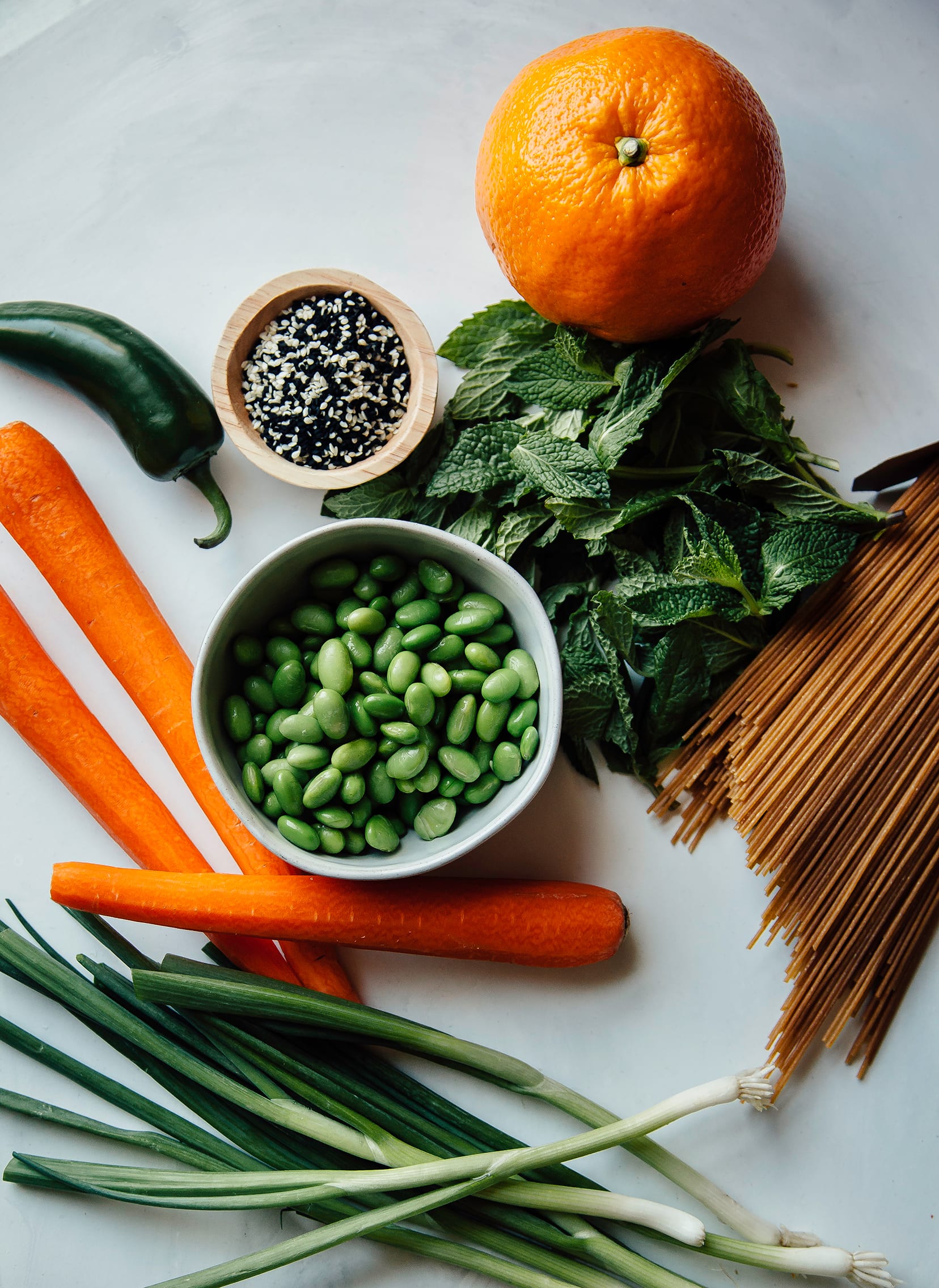 Overhead shot of ingredients for a cold ginger noodle salad with edamame and mint
