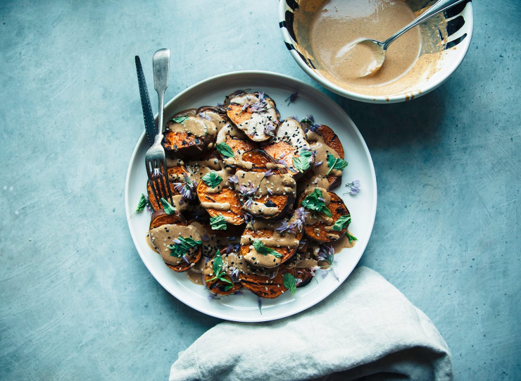 Overhead shot of grilled sweet potatoes with Chile lime tahini sauce with extra sauce in a bowl to the side.