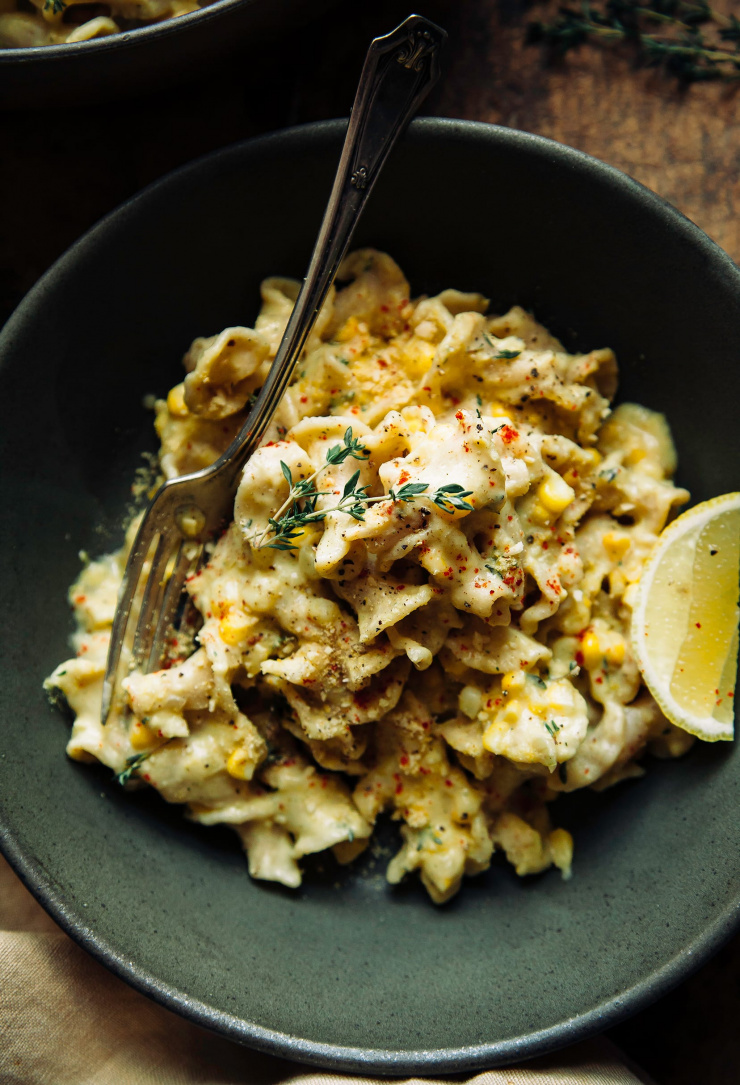 An overhead shot of creamy pasta in a matte, dark green bowl.
