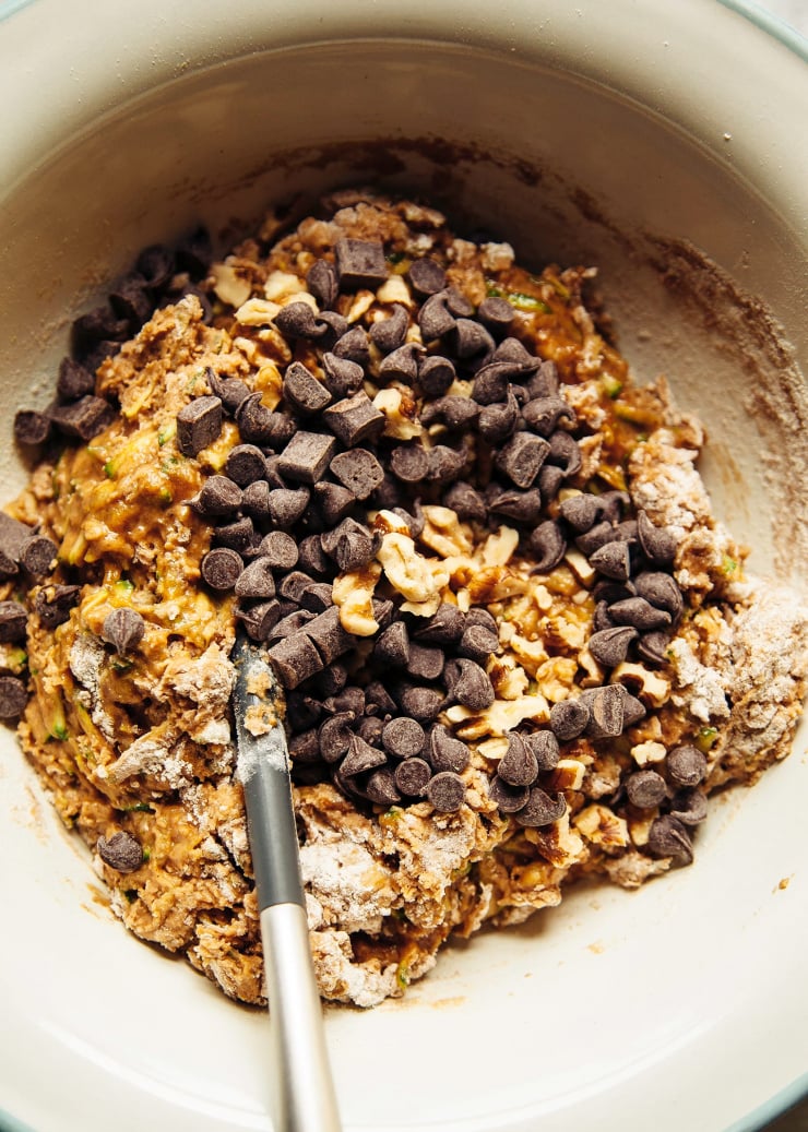 An overhead shot shows a loaf batter coming together in a mixing bowl with chocolate chips and walnuts.