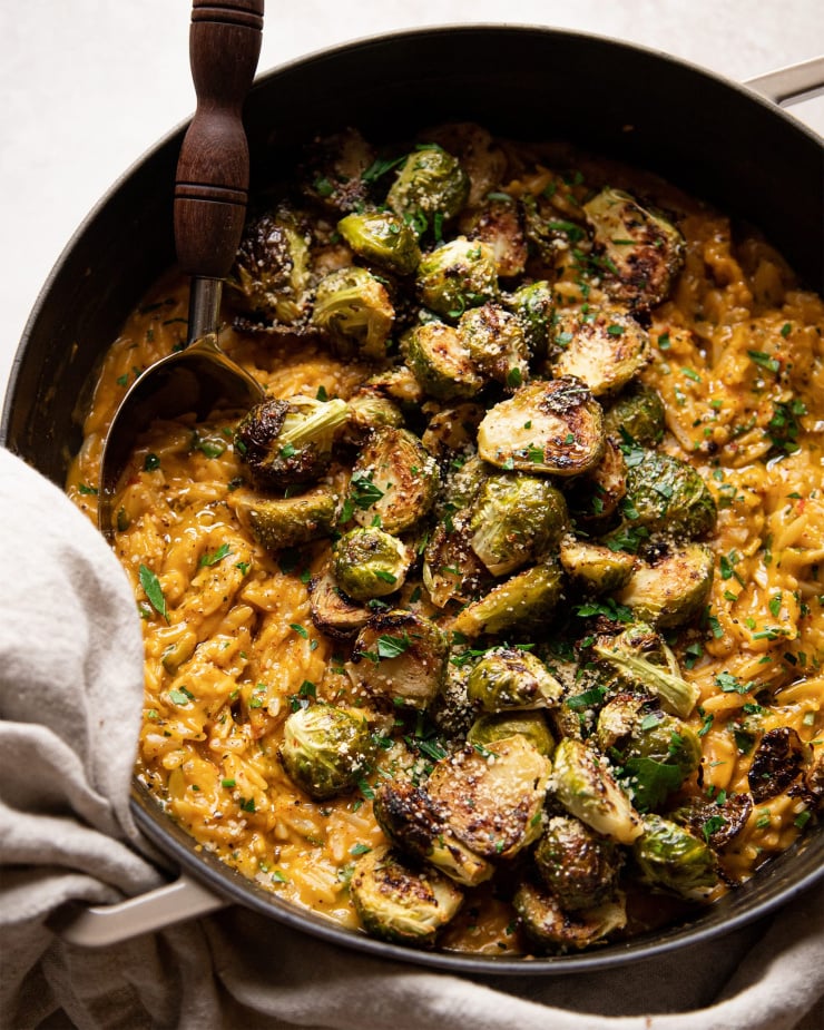 Up close shot of the butternut orzo with a pile of crispy roasted Brussels sprouts on top.
