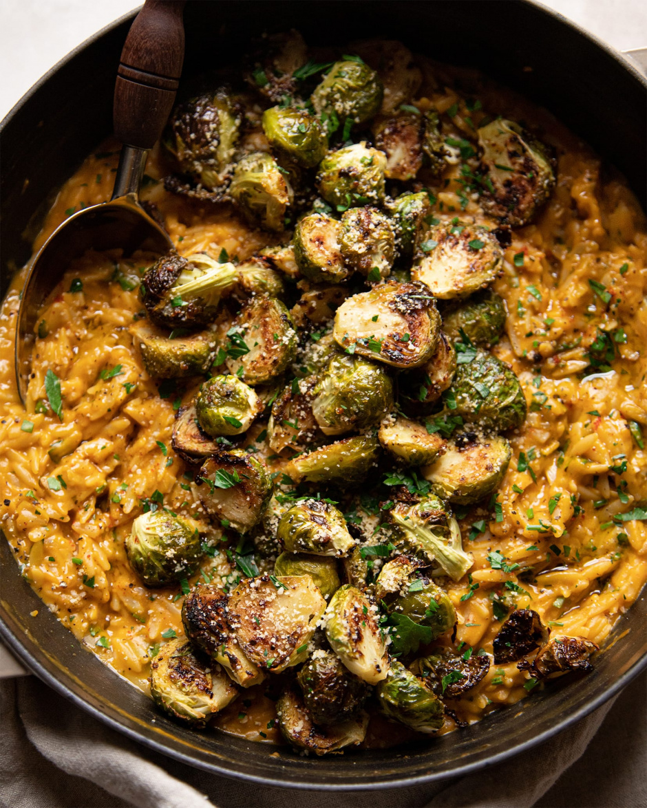 Up close shot of the butternut orzo with a pile of crispy roasted Brussels sprouts on top.