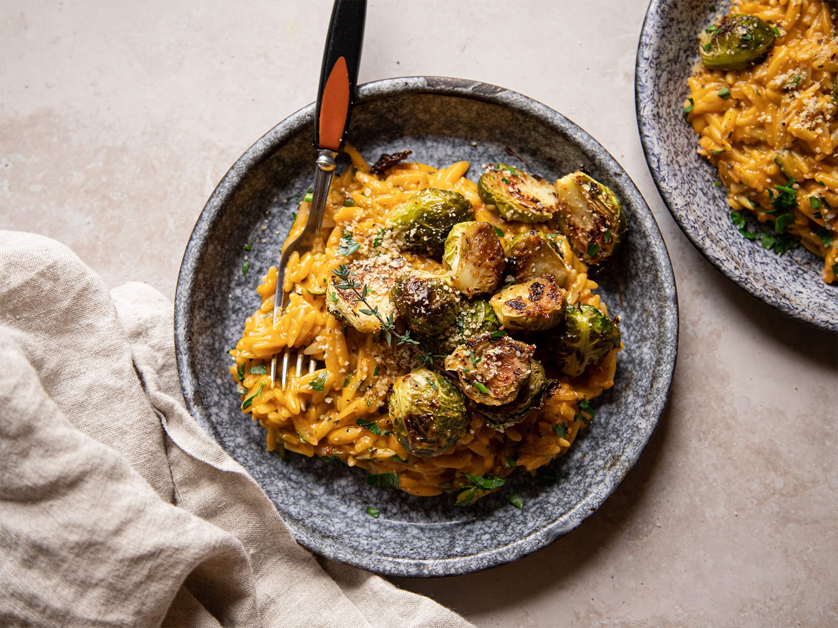 An overhead shot of creamy butternut orzo in a blue, shallow bowl.