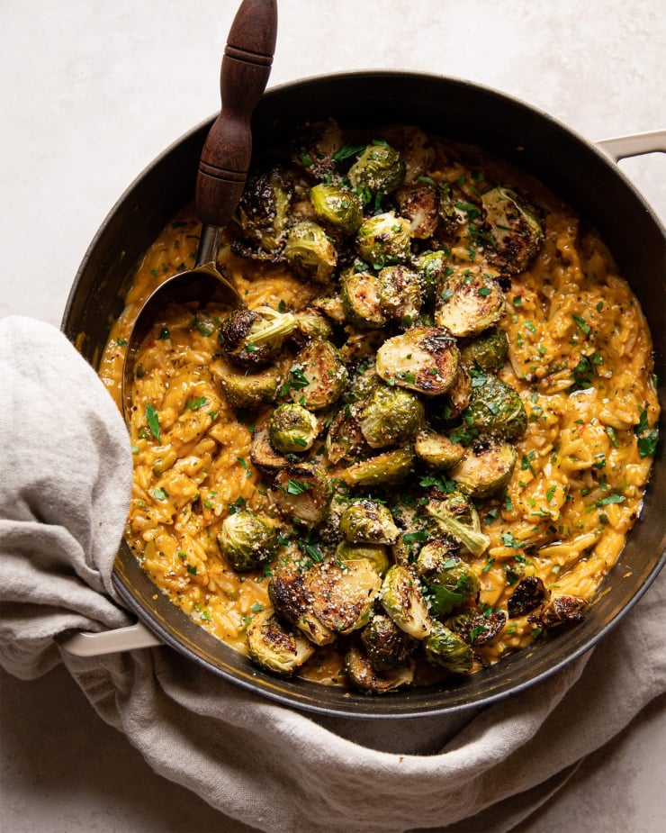 Up close shot of the butternut orzo with a pile of crispy roasted Brussels sprouts on top.