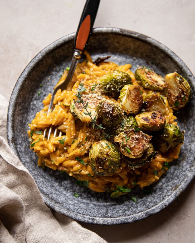 An overhead, up close shot of creamy butternut orzo in a shallow blue bowl.