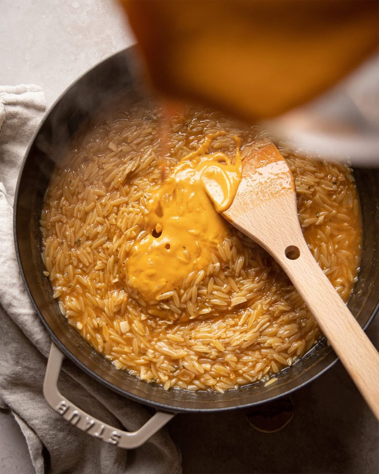 Adding squash to the cooking orzo.
