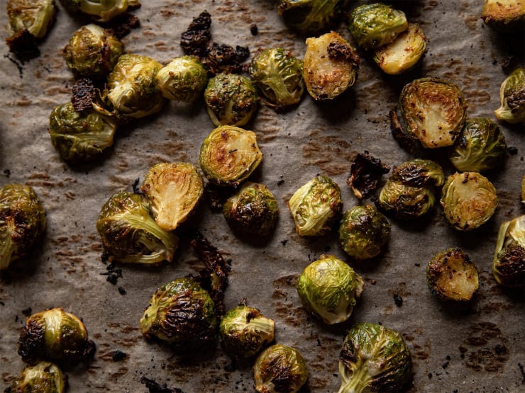 A tray of roasted Brussels sprouts, up close with moody lighting.