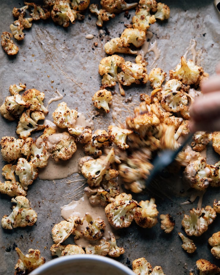 Tossing the cauliflower on a sheet pan.