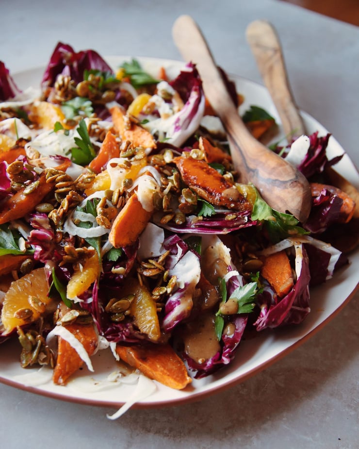 a 3/4 shot of a roasted sweet potato and radicchio salad with coriander candied pumpkin seeds, shaved fennel and orange.