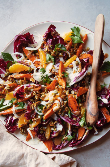 An overhead shot of a roasted sweet potato and radicchio salad with coriander candied pumpkin seeds, shaved fennel and orange.