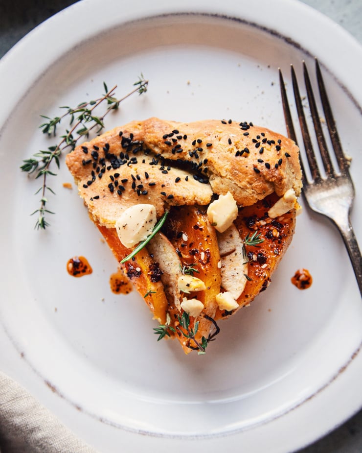 An overhead, up close shot of a slice of vegan butternut galette on a weathered white plate.