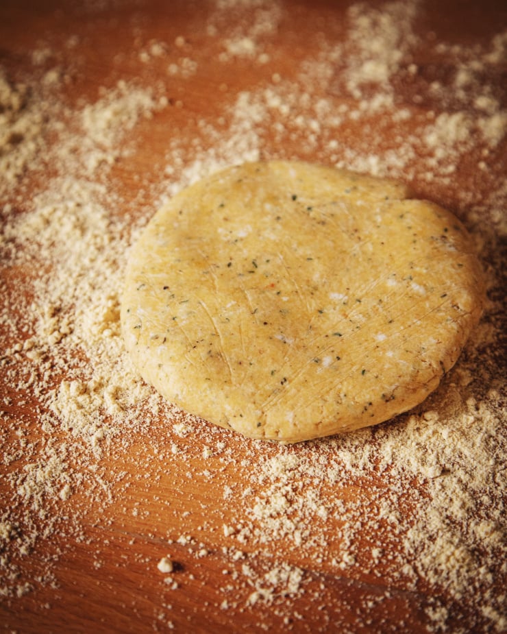 A disc of dough is out on the counter with a dusting of flour.