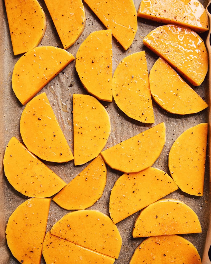 Overhead shot of slices of butternut squash on a parchment-lined baking sheet.