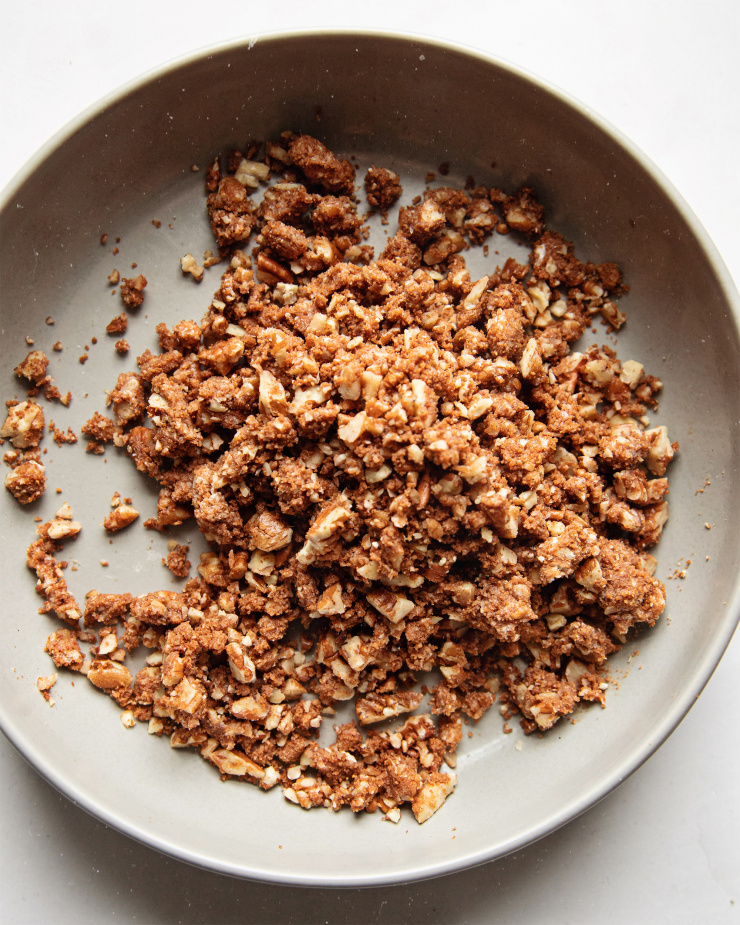 AN overhead shot of finished pecan streusel in a grey bowl on a white background.