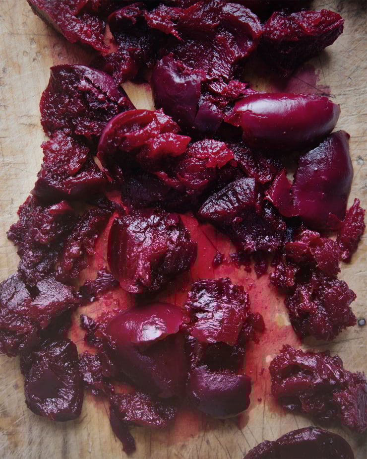 An overhead shot of cooked beets that have been “crushed” on a cutting board.