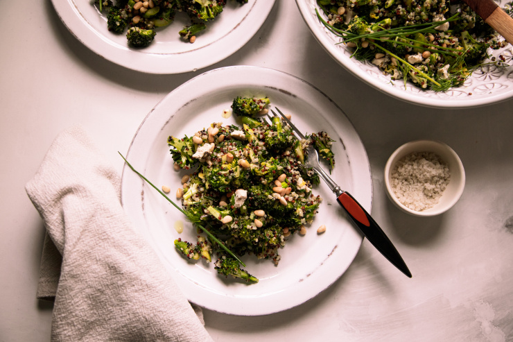 An overhead shot of a green vegetable and quinoa salad on a white plate with a beige napkin nearby
